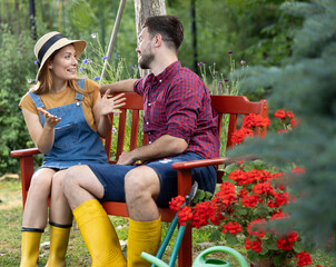 Man and woman taking a break and chatting on bench after garden work