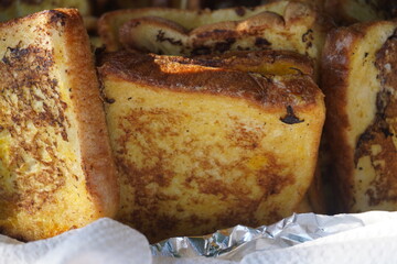 A close-up of delicious avgopites, a traditional fried delicacy from Crete made with bread and eggs, displayed in a woven basket at a local festival.