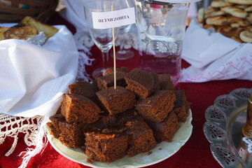 Traditional Cretan petmezopita, a moist sweet cake made with grape molasses, served in a local market setting. Showcasing authentic Greek dessert culture with homemade, rustic charm from Crete.