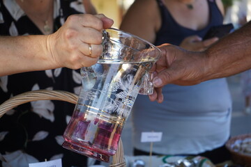 An authentic moment in Crete, Greece, as a local woman pours tsikoudia, also known as rakí, from a beautiful glass pitcher. A warm, traditional gesture of hospitality.