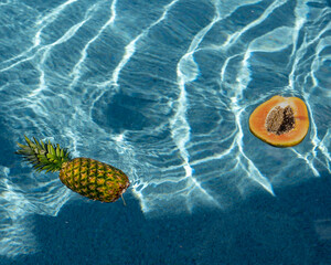 aesthetic fruits floating in blue water pineapples and papaya