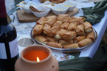 Traditional Cretan sweet mpoureki (μπουρέκι) with myzithra cheese, served beside a glowing candle, creating a warm, inviting Mediterranean atmosphere for festive gatherings.