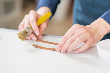 A craftsman uses a brush to cover leather parts. 