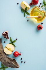 Festive vertical composition for Rosh Hashanah featuring apples, honey, pomegranates, and shofar on blue