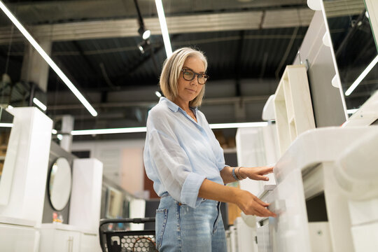 Woman shopping for furniture in a modern store, examining items during daylight hours