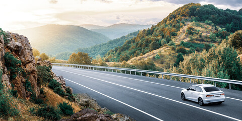 car drive on the mountain road landscape in the panoramic nature. View of travel by car on mountain highway on sunset.  Winter travel trip by car on highway by the panoramic mountain road. 
