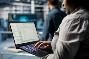Close up of server room coworkers troubleshooting backend operations using software on laptop. Team of data center programmers compiling software patches to fix bugs using notebook