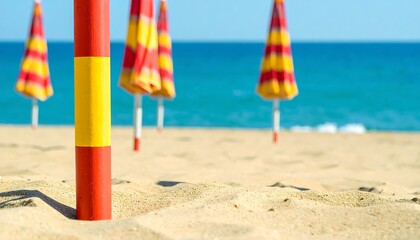 Colorful beach umbrellas stand out against the soft sand, with the ocean's vibrant blue water creating a serene summer scene.