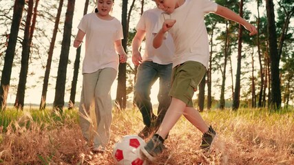 Children sons play football with father on lawn. Dad child cheerfully plays ball on grass in forest. Parent, boy girl children run after red ball in park. Active happy family. Family team sports games