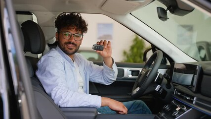 Happy Arab customer showing new car key while sitting inside