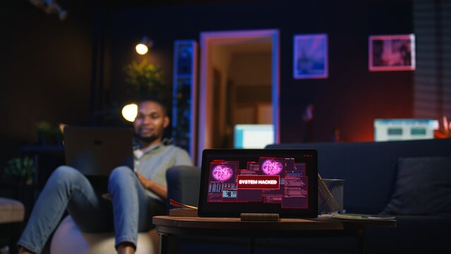 Black IT professional in loft working on cybersecurity with gadgets, tackling hacking attempts, encryption and cyber defense. Screen shows security breach warning, data security risks. Camera A. - Powered by Adobe