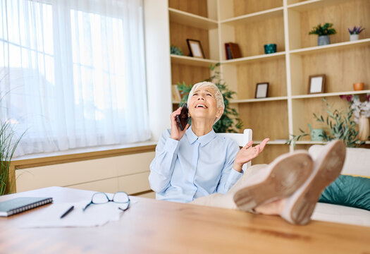 Portrait of a mature senior woman or a  businesswoman working from home having a meeting online, home office, or a student learning, or mature woman having a phone call, holding a mobile phone, smartp - Powered by Adobe