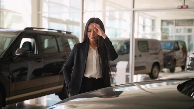 Elegant saleswoman posing near car in dealership