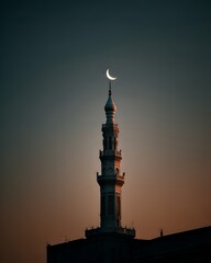 A Serene Image of an Islamic Mosque’s Minaret Rising Against Sunset with a Crescent Moon