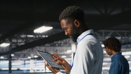 Data center programmer checking lines of code and colleague reviewing AI LLM visualizations. IT experts analyze neural networks outputs to ensure stable infrastructure operations, using tablet