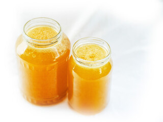 Glass jar of golden bee honey is on a white background. Fine organic product concept. Agriculture and food industry.