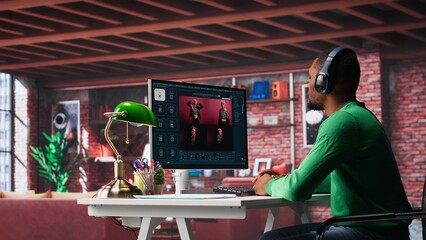 African American worker using generative AI program with photos in a modern loft. Young man creating visual content with deep learning models and prompts on monitor with AI interface. Camera A.