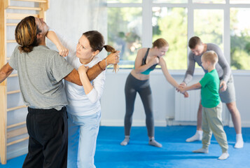 Woman and man in group self-defense classes practicing sparring technique of blowing to chin in gym