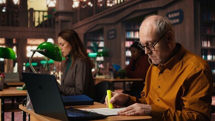 Elderly student using highlighter pen to memorize lesson papers, applying a study strategy with essential information from courses. Old man works on memorization for exams.