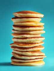 Stack of pancakes on cyan background with crisp edges, photo