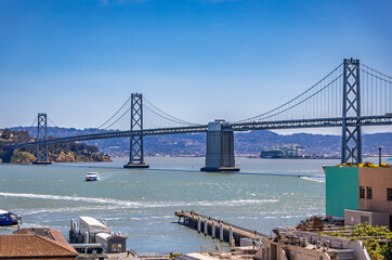 San Francisco Bay Bridge across the bay with a ferry boat on a bright sunny day