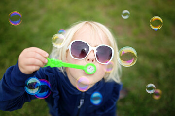 Little Girl Child Blowing Bubbles Outside on a Summer Day