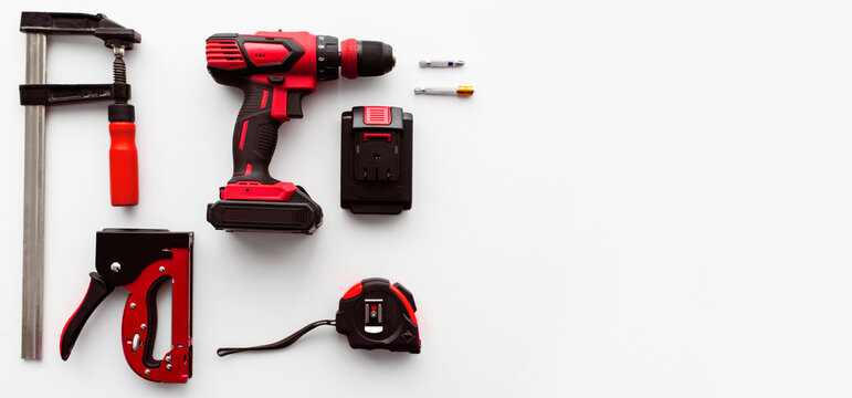 Building instrument set on the white background, panorama with free space. Electric drill, ruler and clamp tools flat lay. Top view of professional instrument, copy space