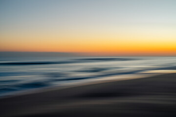 Abstract blurred seascape with vibrant orange, purple, and blue hues during sunset.