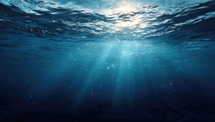 Sunbeams penetrate deep blue ocean water, illuminating suspended particles and creating dramatic shadows on the seabed