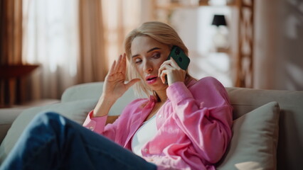 Upset woman talking mobile phone at sunny room closeup. Girl feeling headache