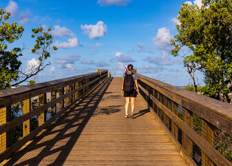 Female Hiker Crossing Wooden Bridge to Lovers Key Beach, Lovers Key State Park, Florida, USA