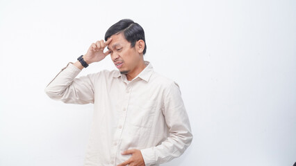 Asian young man showing stress gesture with hand touching forehead, studio shot