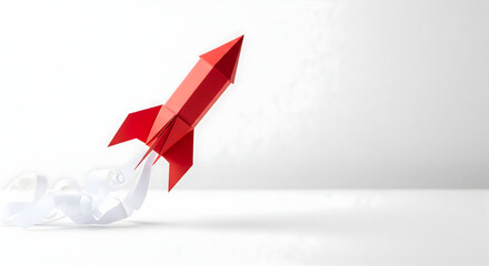 Red origami rocket launching upwards with white paper smoke trail