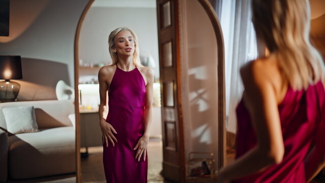 Blonde trying party dress planning outfit gazing reflection. Sexy woman look