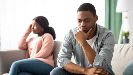 Upset black couple young man and woman having relationships crisis, sitting on couch and looking aside, sad african american family thinking about divorce. Crisis in marriage concept