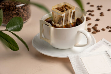 Drip bag of fresh drink in a glass with coffee beans. Drip coffee using a paper type filter.