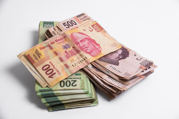 billetes mexicanos de distintos valoresm colocados unos sobre otros, acercamiento sobre fondo blanco
