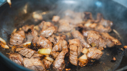 Juicy cubed beef sizzling with garlic and spices in a frying pan. Perfect for cooking demos, recipe videos, or food ads. Appetizing close-up