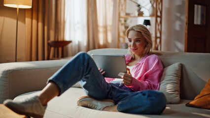 Girl student reading pad computer at living room sofa. Laughing woman relaxing © stockbusters