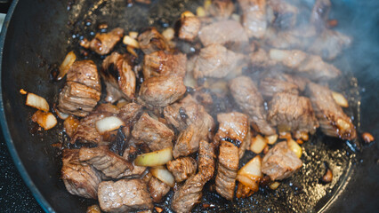 Juicy cubed beef sizzling with garlic and spices in a frying pan. Perfect for cooking demos, recipe videos, or food ads. Appetizing close-up