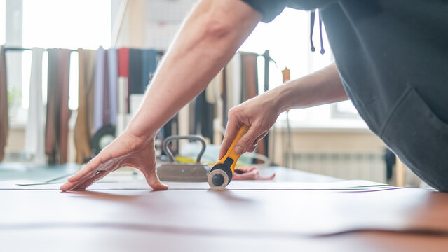 Leatherworker measuring and cutting leather in workshop.  - Powered by Adobe