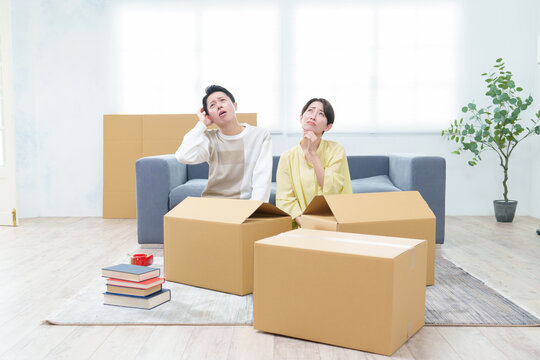 困った表情でダンボールを整理するカップル