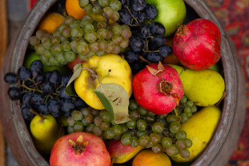 Food photo. Top view. Plate with tasty ripe fresh juicy red pomegranate, grape, yellow apple, pear. Fruit counter stall at street farm market on harvest festival Tbilisoba, autumn city holiday. Lunch 