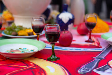 Horizontal defocused photo. Glass of red wine, fruit plate on festive table of street fast food cafe on city holiday Tbilisoba, wine market, autumn harvest fair, New Year festival, bar, pub. Drink
