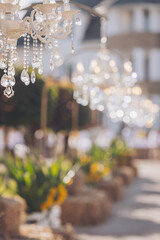 Luxurious crystal chandeliers in the middle of a forest in the glow of the sunset. Fabulous wedding decor with chandeliers. Decorating a with antique chandeliers. Light bulb in the shape of a candle.
