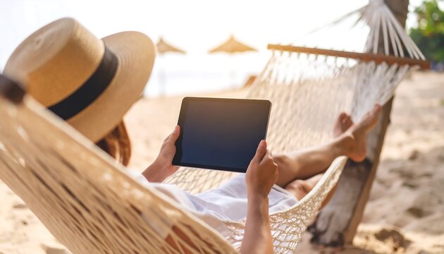 Woman relaxing on beach hammock with tablet (1)