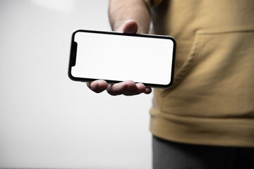 Latin man holding a smartphone in his hand with a blank screen isolated on white background with clipping path.