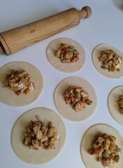 Argentina chicken empanada pasty preparation on white table with rolling pin.