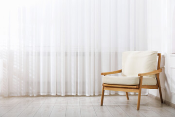Comfortable armchair near window indoors, space for text
