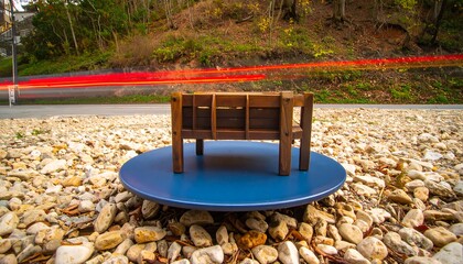 Obraz premium Wooden bench on a blue circular base amidst gravel